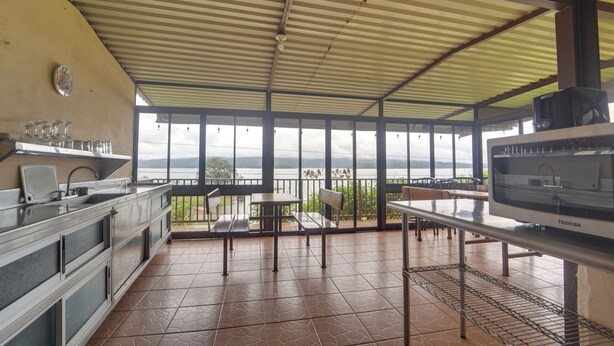 Uma cozinha com vista para um lago, uma sala de jantar com mesas e cadeiras, e uma janela grande.