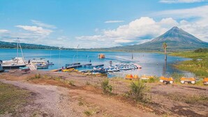 Uma marina com barcos atracados, céu claro e uma montanha ao fundo.