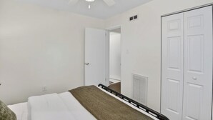 A bedroom with a bed, a ceiling fan, a white door, and a white closet. - Golf & Chill! Family-Friendly Augusta Home (Augusta)