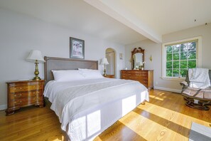 A bedroom with a large bed, wooden dresser, and a rocking chair. - Charming Waterfront Home with Mt Rainier View (Olympia)