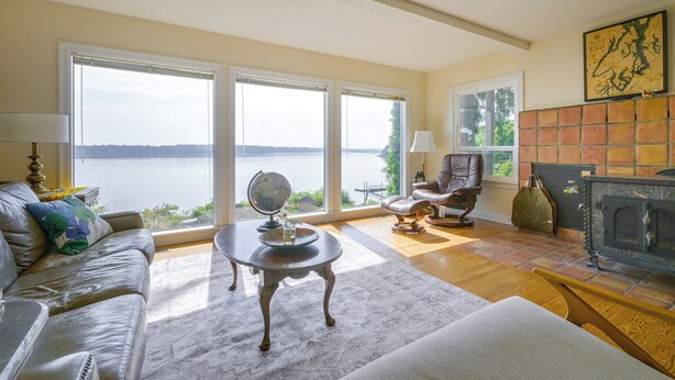 A living room with a fireplace, a globe, and a view of a body of water. - Charming Waterfront Home with Mt Rainier View (Olympia)
