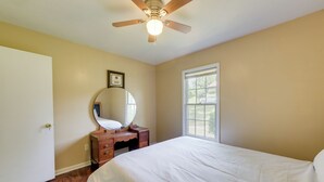 A bedroom with a bed, a dresser, a mirror, a ceiling fan, and a window. - Columbus Home Near Parks, Shops & Dining (Columbus)