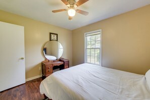 A bedroom with a bed, a dresser, a mirror, a ceiling fan, and a window. - Columbus Home Near Parks, Shops & Dining (Columbus)