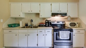 A kitchen with white cabinets, a stainless steel stove, a microwave, and a coffee maker. - Columbus Home Near Parks, Shops & Dining (Columbus)