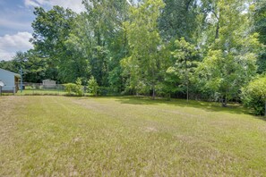 A grassy yard with trees and a building in the background. - Columbus Home Near Parks, Shops & Dining (Columbus)