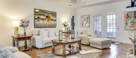 A spacious living room with a ceiling fan, a large painting, and a fireplace.