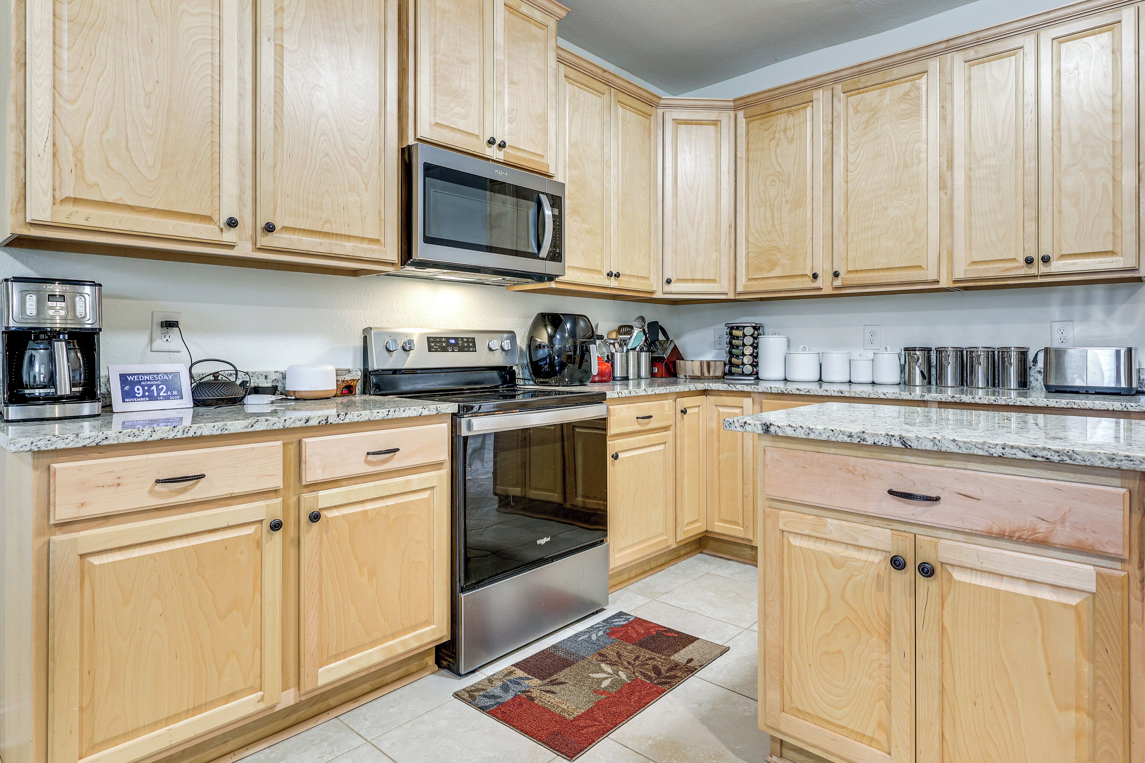 A kitchen with wooden cabinets, a microwave, a stove, and various kitchen appliances.