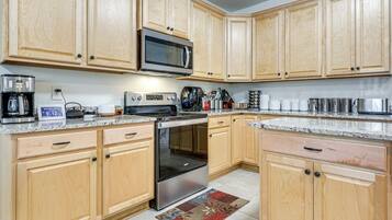 A kitchen with wooden cabinets, a microwave, a stove, and various kitchen appliances.