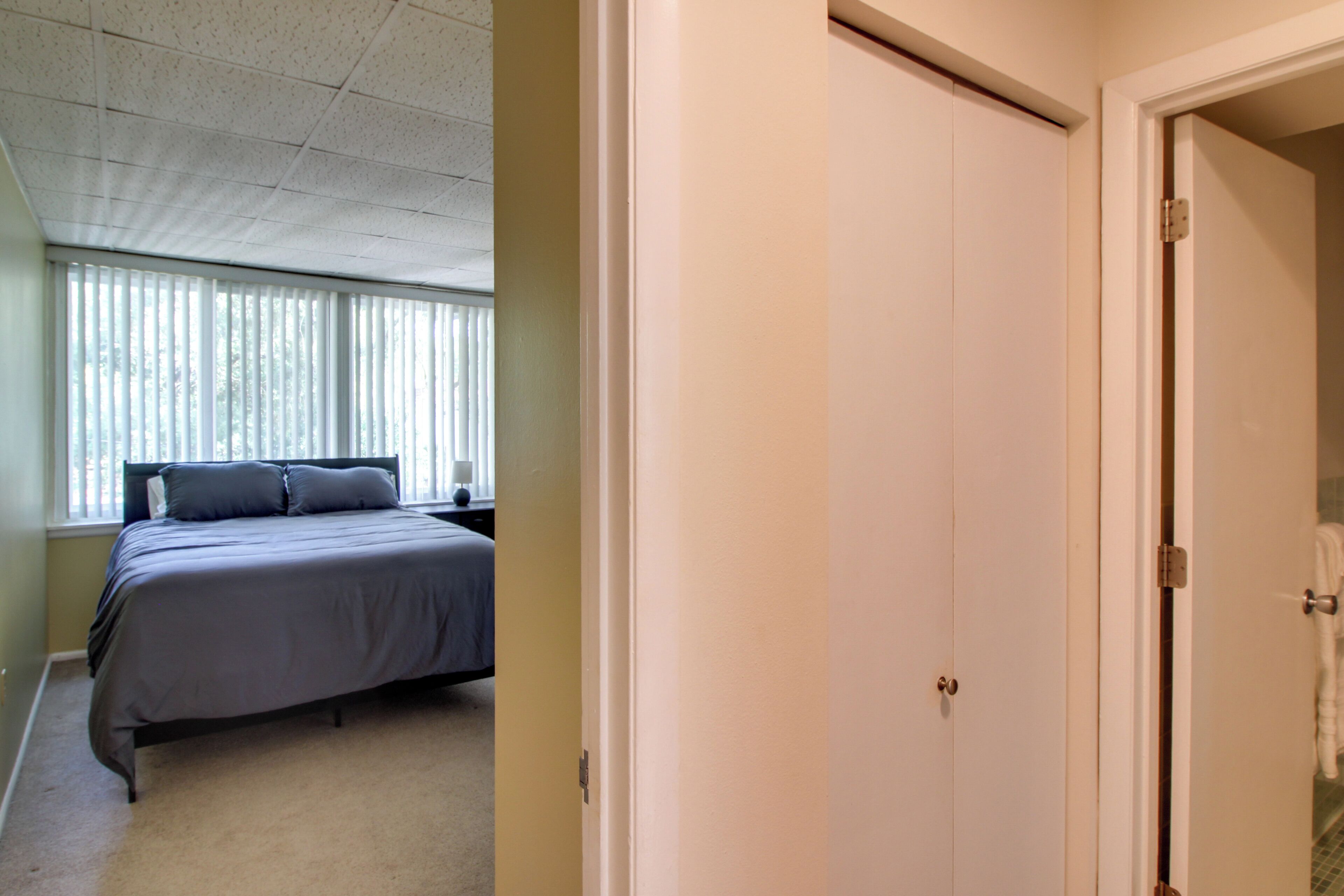 Una camera da letto con un letto, una finestra con persiane e una porta.