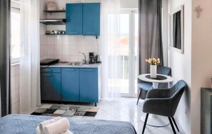A compact hotel room with a kitchenette, a small dining area with a table and chairs, and a bed with a patterned bedspread. - Awesome apartment in Hvar with swimming pool (Hvar)