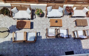 An outdoor seating area with multiple wooden loungers, a round table, and potted plants. - Awesome apartment in Hvar with swimming pool (Hvar)