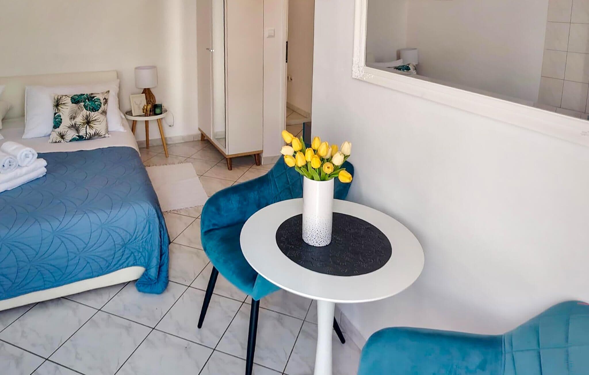 A hotel room with a bed, a small table with a vase of flowers, a chair, and a window.