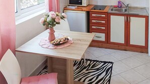 Een kleine kitchenette met een magnetron, spoelbak en houten kastjes.