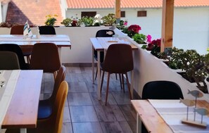 An outdoor dining area with tables and chairs, surrounded by potted plants and flowers. - Awesome apartment in Hvar with house sea view (Hvar)