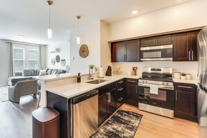 A modern kitchen with dark cabinetry, stainless steel appliances, and a central island. - Walk to Cleveland Clinic! Contemporary Townhome (Cleveland)