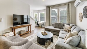 Ein modernes Wohnzimmer mit Fernseher, Sofa, Couchtisch und einem Essbereich mit Stühlen und Tisch.