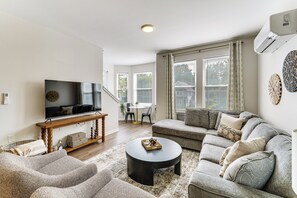 A modern living room with a television, sofa, coffee table, and a dining area with chairs and a table. - Walk to Cleveland Clinic! Contemporary Townhome (Cleveland)