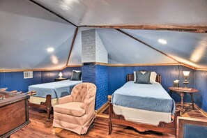 Ein Zimmer mit zwei Betten, einem Sessel, einem Schreibtisch und einer Lampe.
