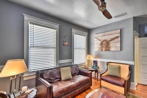A living room with a leather sofa, two armchairs, a ceiling fan, and a large window with blinds. - Daytona Beach 2-Unit Combo Near Halifax River (Daytona Beach)