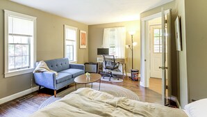 Ein Zimmer mit einem Bett, einem Schlafsofa, einem Couchtisch, einem Schreibtisch mit Computer und einer Lampe.