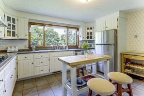 A kitchen with white cabinets, a wooden countertop, a stainless steel refrigerator, and a window with a view of trees. - Perfect Family Retreat: Pool, Fire Pit (Westfield)
