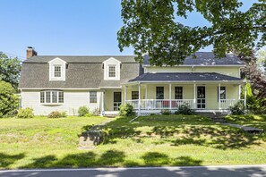 A two-story house with a front porch, a chimney, and a well-maintained lawn. - Perfect Family Retreat: Pool, Fire Pit (Westfield)