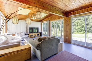 A modern living room with a wooden ceiling, large windows, and a flat-screen TV. - Perfect Family Retreat: Pool, Fire Pit (Westfield)
