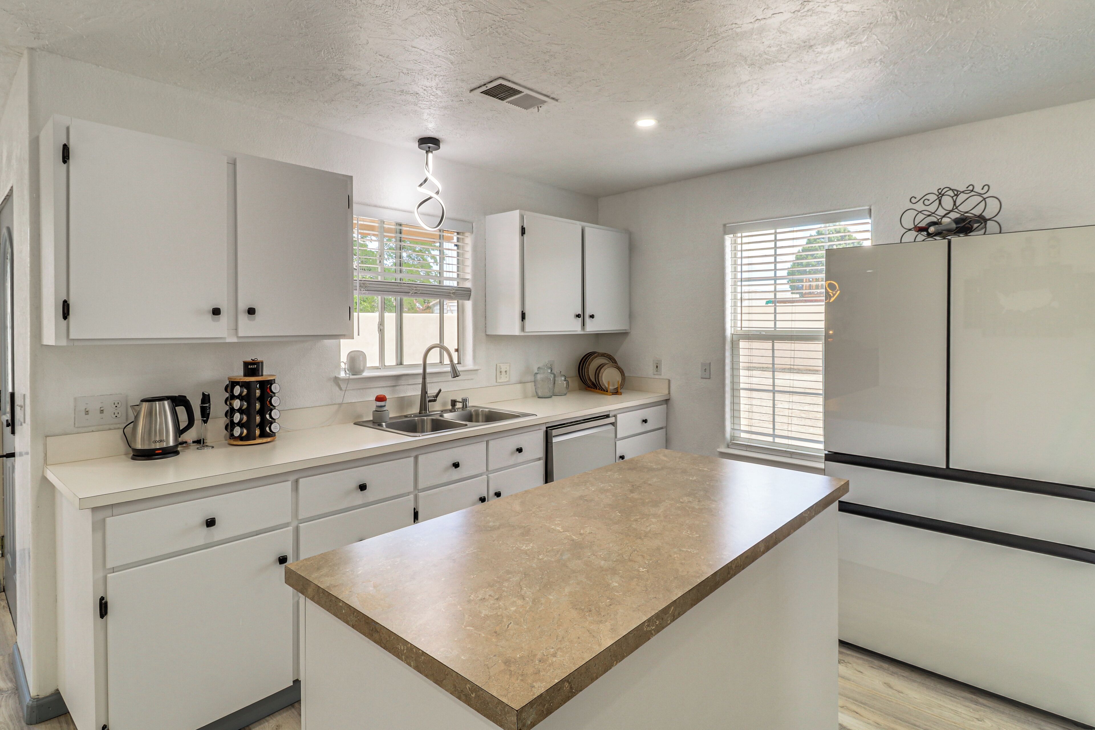 A modern kitchen with white cabinets, a central island, and a built-in refrigerator.