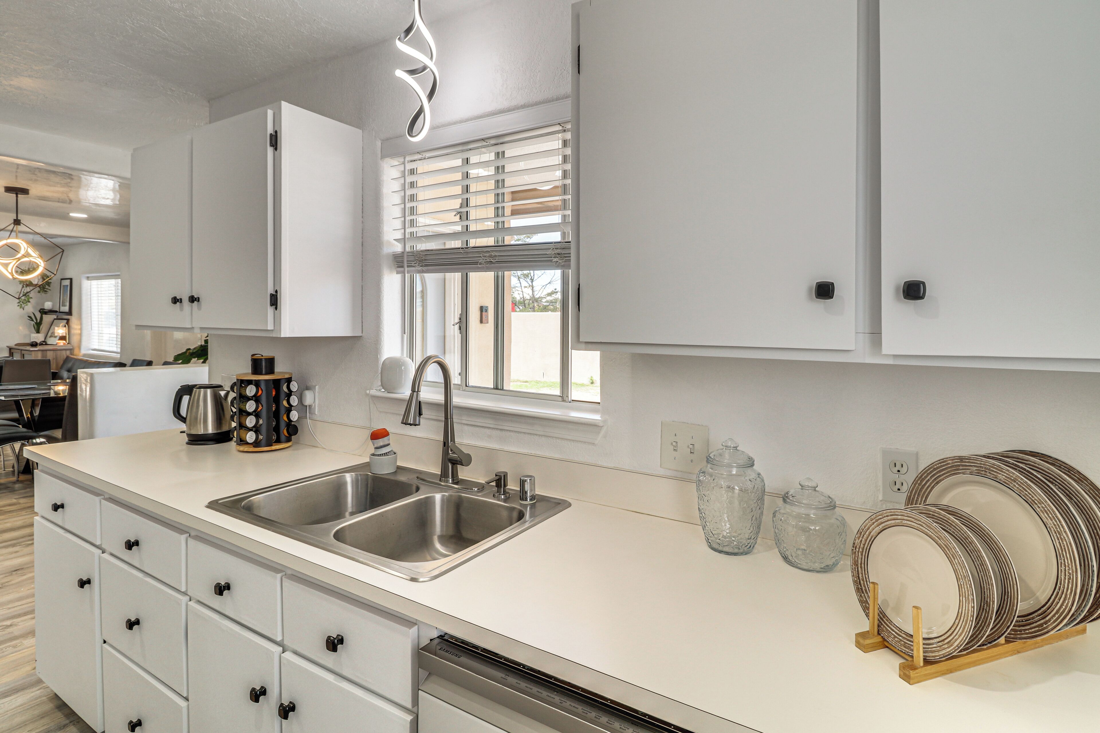 A modern kitchen with white cabinetry, stainless steel appliances, and a built-in dishwasher.