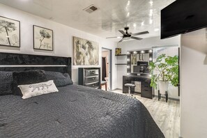 Ein modernes Schlafzimmer mit einem großen Bett, einem Deckenventilator und Kunstwerken an den Wänden.