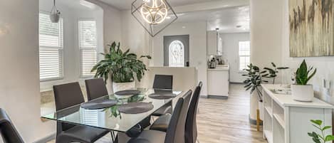Un comedor moderno con una mesa de vidrio, sillas negras y una lámpara colgante de diseño geométrico.