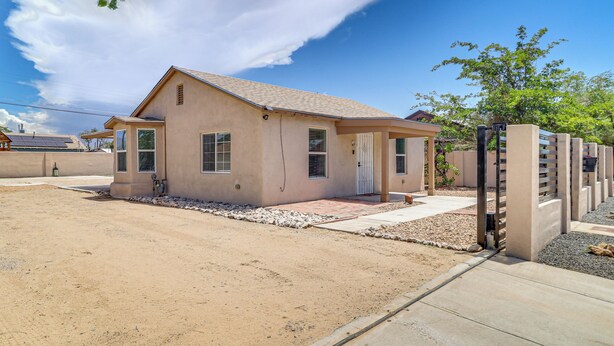 A single-story house with a sloped roof, a front porch, and a small front yard with a gravel pathway. - Room for 6 Cars on Balloon Fiesta Weekend (Albuquerque)