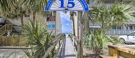 A wooden boardwalk leading to a beach entrance with a sign reading "15 Public Beach Access".