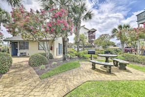 A courtyard with a paved walkway, stone benches, and flowering trees. - Pool Days + Beach Strolls! Ground-Floor PCB Condo (Panama City Beach)