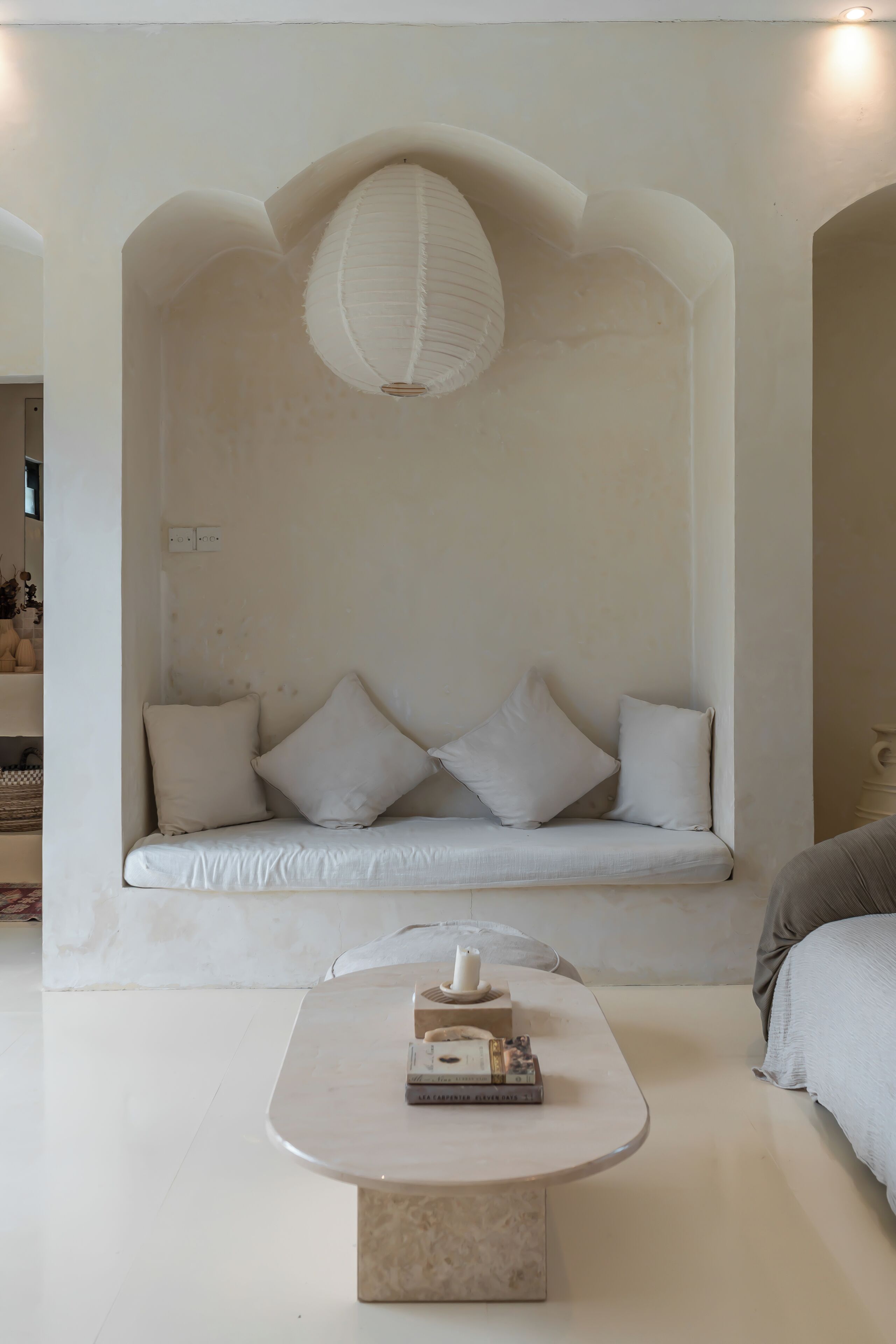 Habitación minimalista con sofá blanco, una mesita redonda y una lámpara colgante.