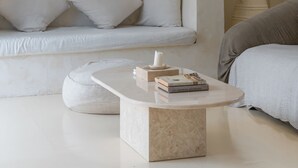 Ein stilvolles Wohnzimmer im minimalistischen Stil mit einem weißen Sofa, einem runden Couchtisch mit Büchern und einer Pendelleuchte.