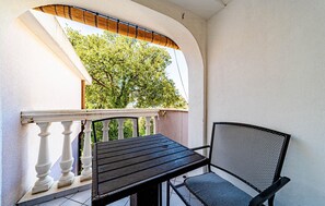 A balcony with a table and chair, a white balustrade, and a view of a tree. - Amazing apartment in Viganj with WiFi (Viganj)