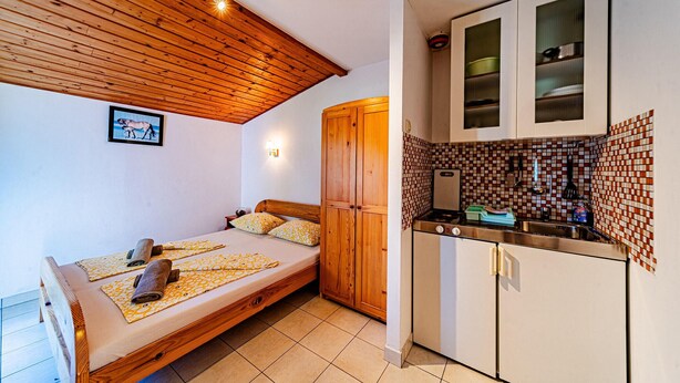 A compact room with a bed, wooden ceiling, a small kitchenette, and a tiled backsplash. - Amazing apartment in Viganj with WiFi (Viganj)