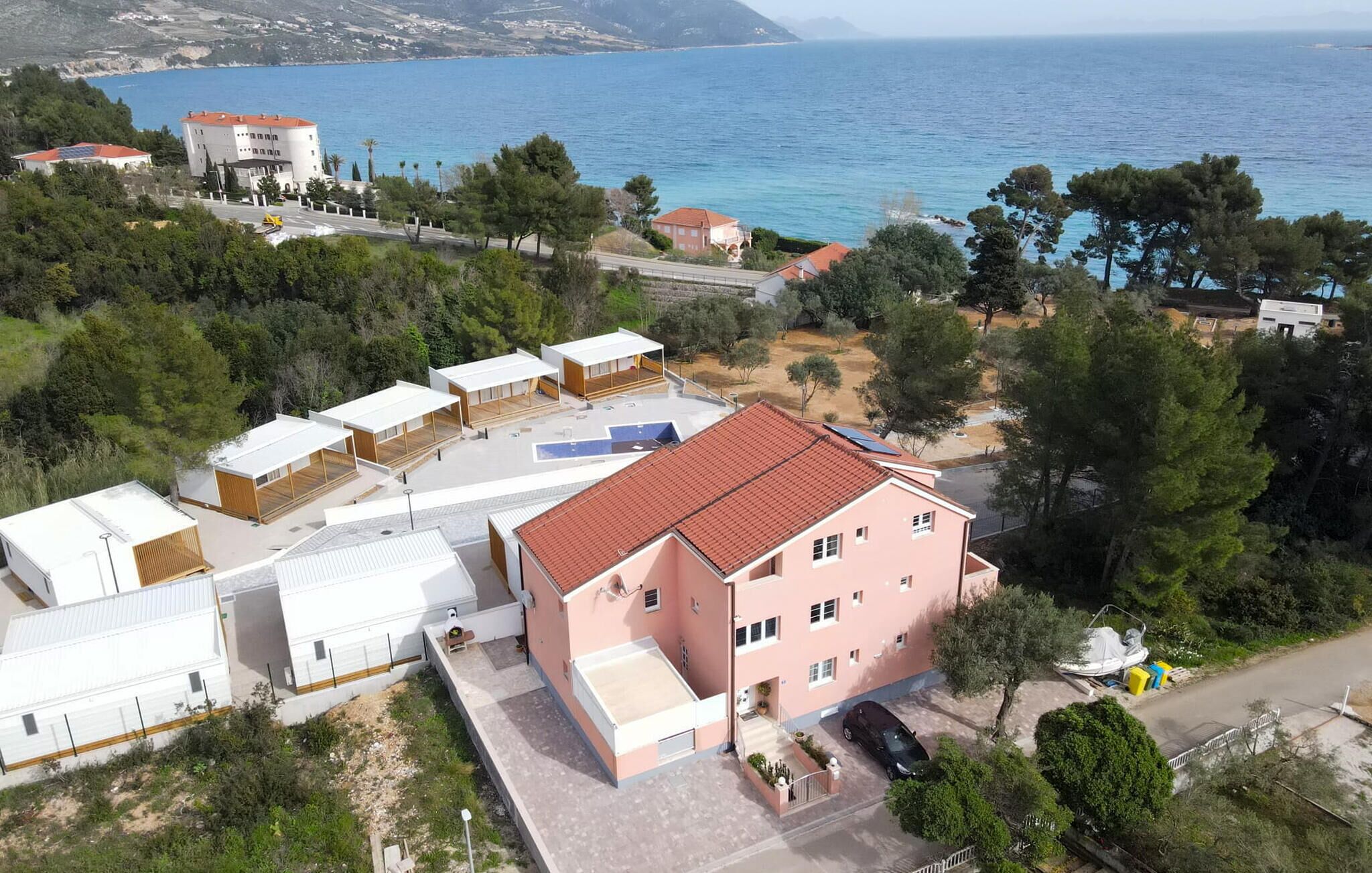 A coastal property with multiple buildings, a swimming pool, and a view of the sea.