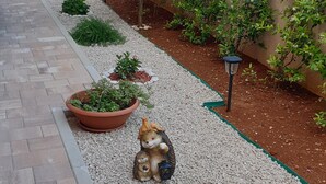 A garden pathway with potted plants and a decorative squirrel statue. - Gorgeous apartment in Orebic with WiFi (Orebic)