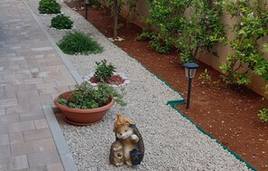A garden pathway with potted plants and a decorative squirrel statue. - Gorgeous apartment in Orebic with WiFi (Orebic)