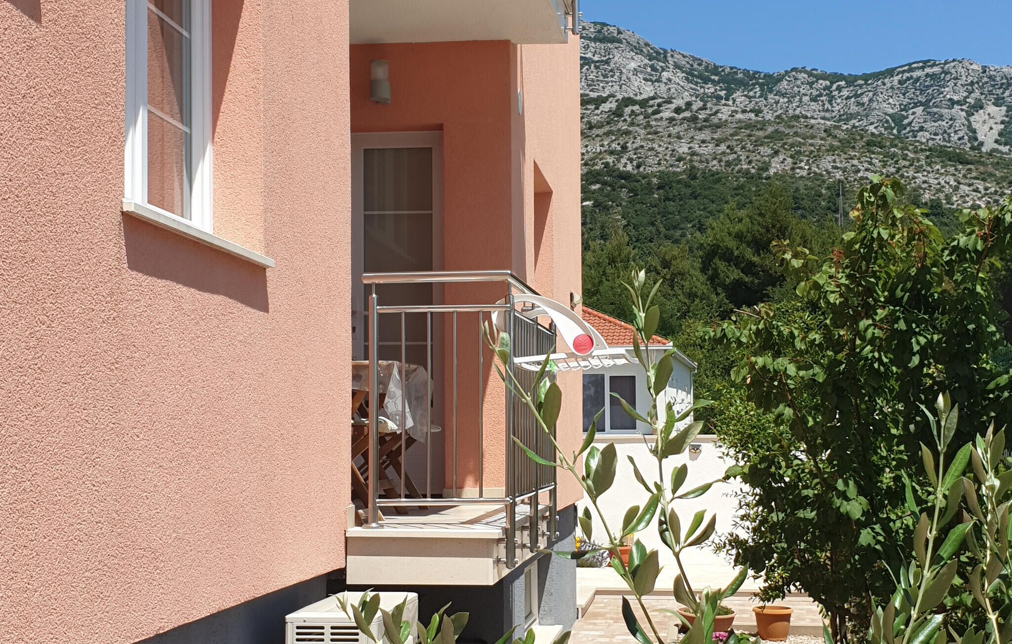 A building with a balcony, a door, and a view of a mountainous landscape.