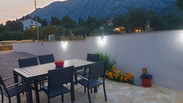 An outdoor patio with a table and chairs, a white wall, and a mountain in the background. - Gorgeous apartment in Orebic with WiFi (Orebic)