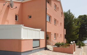 A multi-story building with a flat roof, white shutters on the ground floor, and a small outdoor area with steps leading to a door. - Gorgeous apartment in Orebic with WiFi (Orebic)