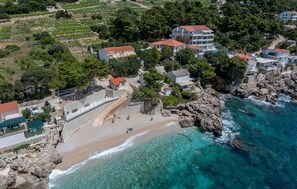 A coastal area with buildings, a beach, and rocky terrain.
