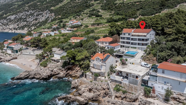 Uma área residencial costeira com casas, piscina e terreno rochoso.