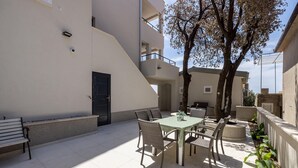 Área de pátio com mesa, cadeiras, um banco e uma porta.