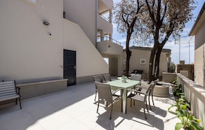 Ein Patio mit Tisch, Stühlen und einer Bank, sowie einer Tür.