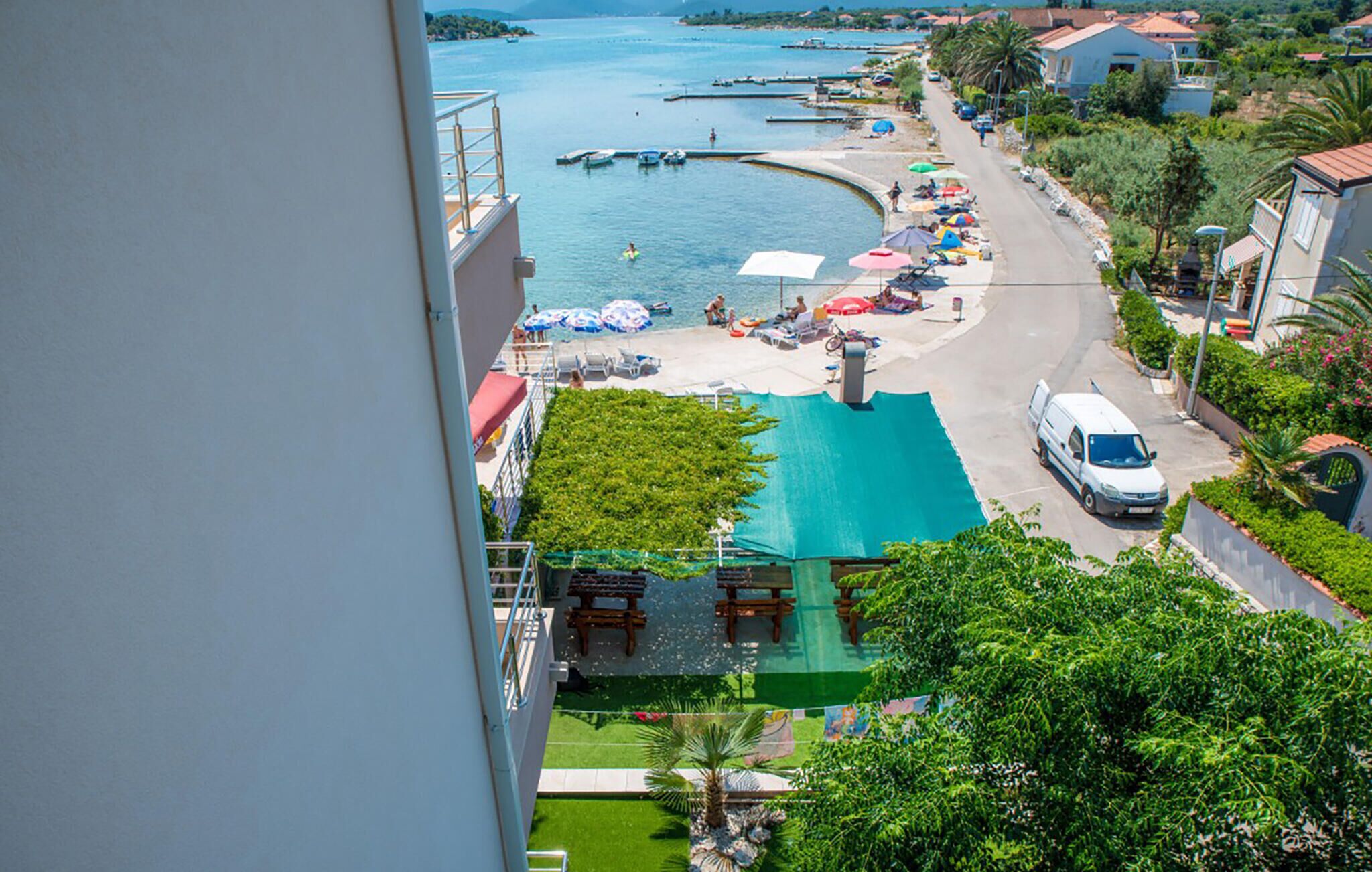 Une vue sur la côte avec une piscine, des parasols de plage et des bateaux.