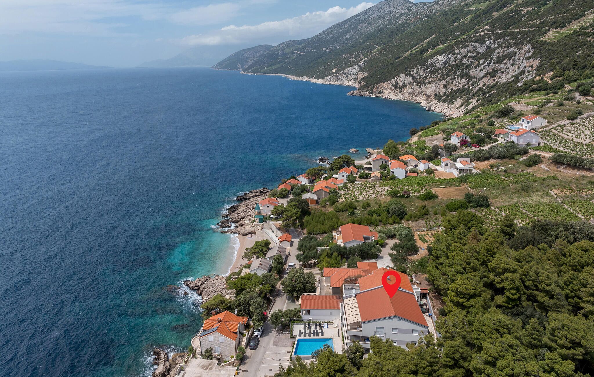 Un pueblo costero con casas, piscina y vistas al mar.